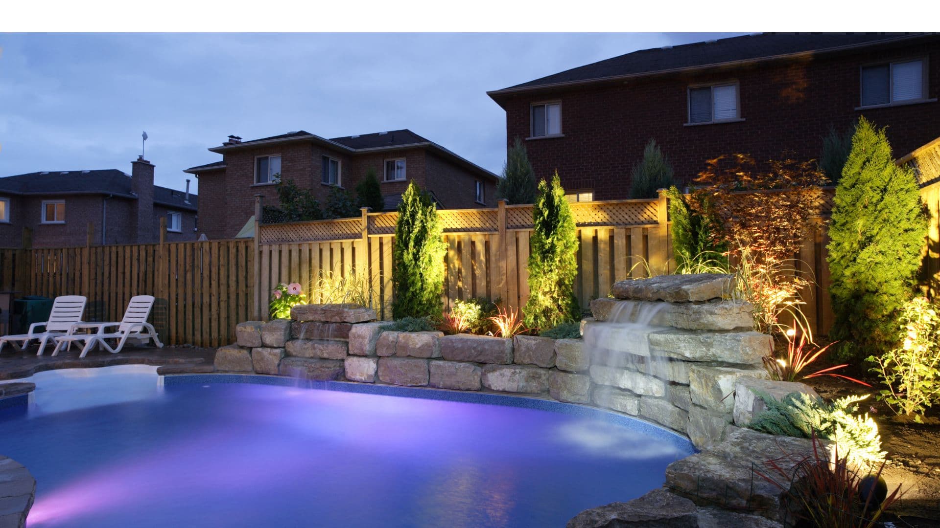 Garden and pool waterfall illuminated with professional landscape lighting